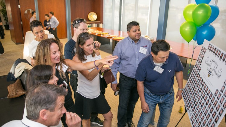 A group of MBA 2007 graduates at their 10-year reunion looking at their graduation class composite